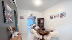 Ein Essbereich mit einem Glastisch, gemütlichen Stühlen, einer Holzschrank und Bildern an der Wand.