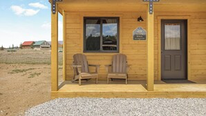 Un edificio in legno con due poltrone Adirondack all'esterno, una porta e una finestra.