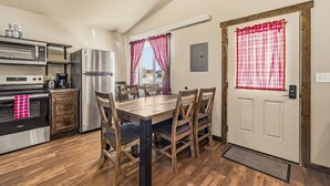 Una cucina compatta con elettrodomestici moderni, un tavolo da pranzo con sedie e una porta con tenda a quadri.