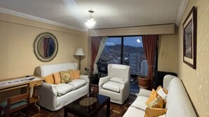 Una sala de estar con sofá, sillón y un escritorio con lámpara.