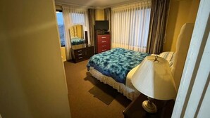 Una habitación de hotel con cama, televisor, cómoda y una silla.