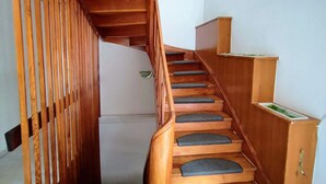 A wooden staircase with a handrail, leading to a landing with a small cabinet. - Accommodation for up to 25 people / from 15-per person (Waldbronn)