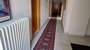 A hallway with a radiator, patterned carpet, and doors leading to rooms. - Accommodation for up to 25 people / from 15-per person (Waldbronn)