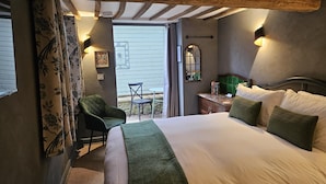 A bedroom with a large bed, a chair, a small table, and a window.