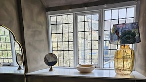 A room with a desk, a window with a view, a lamp, and a mirror.