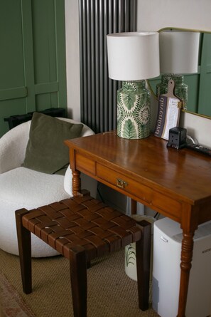 A room with a wooden desk, a white chair, a small wooden stool, a lamp, and a bookshelf. - Cotswold Cottage Guest House (Stow-on-the-Wold)