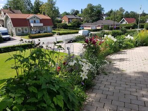 A residential area with houses, a paved walkway, and a garden with various plants.