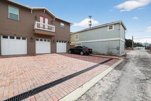 A residential area with a two-story house, a car parked in the driveway, and a small utility building. - Stylish Tampa Home: Complimentary Coffee&Wine Bar (Tampa)