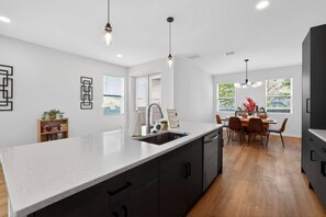 A modern kitchen with a large island, dark cabinetry, and pendant lighting. - Stylish Tampa Home: Complimentary Coffee&Wine Bar (Tampa)