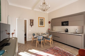A modern kitchen with a microwave, sink, and dining area with chairs and a table. - Violin Suite (Pisa)