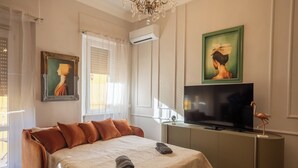 Habitación de hotel con una cama grande, un televisor de pantalla plana, un cuadro y una araña.