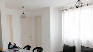 Uma área de refeições com uma mesa, cadeiras e um banco. Há duas luminárias pendentes sobre a mesa.