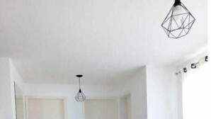 Uma sala de estar moderna com área de jantar, apresentando um sofá cinza, uma mesa de jantar com cadeiras e um pendente.