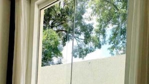 Quarto com porta de vidro deslizante que dá para uma área externa gramada.