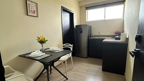 Una cocina compacta con zona de comedor, un refrigerador negro y una ventana que proporciona luz natural.