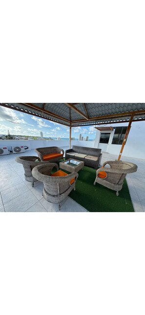 A covered outdoor seating area with wicker furniture and a view of the city. - Hermoso y tranquilo lugar, donde podrás disfrutar lo mejor de la ciudad (Manta)