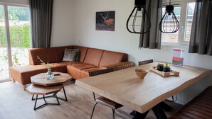 Ein modernes Wohnzimmer mit einer braunen Ledersofa, einem Holzesstisch und einem großen Fenster mit Vorhängen.
