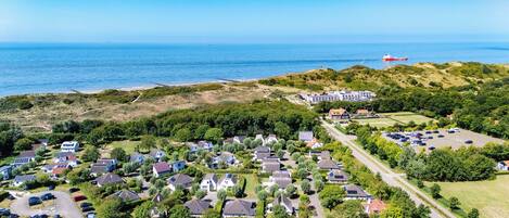 Vista aérea de una zona residencial costera con casas, un estacionamiento y una playa.
