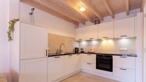 A modern kitchen with white cabinets, a black countertop, and a built-in oven. - Holiday home - Schoolstraat 6a | Vrouwenpolder (Vrouwenpolder)