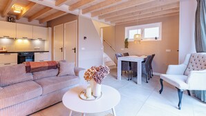 A modern living room with a sofa, a round table with a vase, and a dining area with a table and chairs. - Holiday home - Schoolstraat 6a | Vrouwenpolder (Vrouwenpolder)