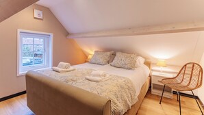 A bedroom with a bed, a chair, a nightstand, and a window. - Holiday home - Schoolstraat 6a | Vrouwenpolder (Vrouwenpolder)