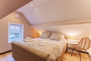 A bedroom with a bed, a chair, a nightstand, and a window. - Holiday home - Schoolstraat 6a | Vrouwenpolder (Vrouwenpolder)