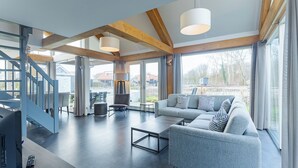 Een moderne woonkamer met een grijze bank, een salontafel en een trap met blauwe leuningen.
