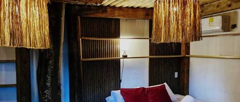 A room with a bed, a wooden ceiling, and two hanging lamps.