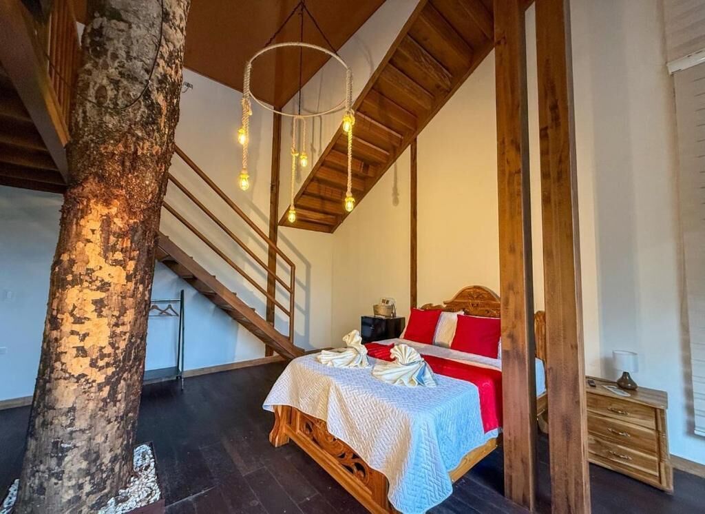 Une chambre à coucher avec un lit en bois, un tronc d’arbre et un escalier.