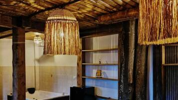 Una habitación rústica con techo de madera, una cama grande, una bañera y un estante de madera.