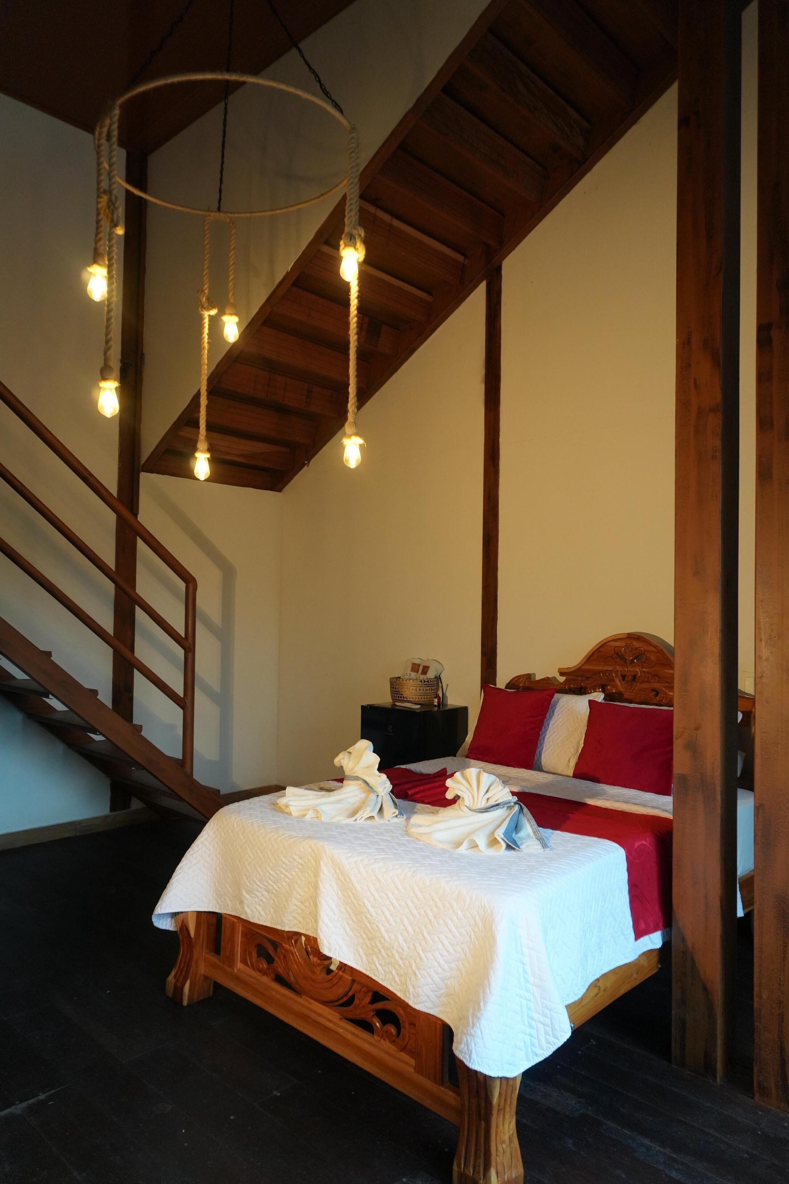 Een slaapkamer met een houten bed, een witte spreidek en een hanglamp.