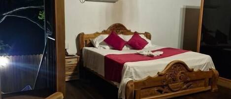 Un dormitorio con techo de madera, una cama con colcha blanca y roja, una silla de madera y un equipo de aire acondicionado en la pared.