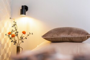 Ett sovrum med en säng, en vägglampa och en vas med blommor.