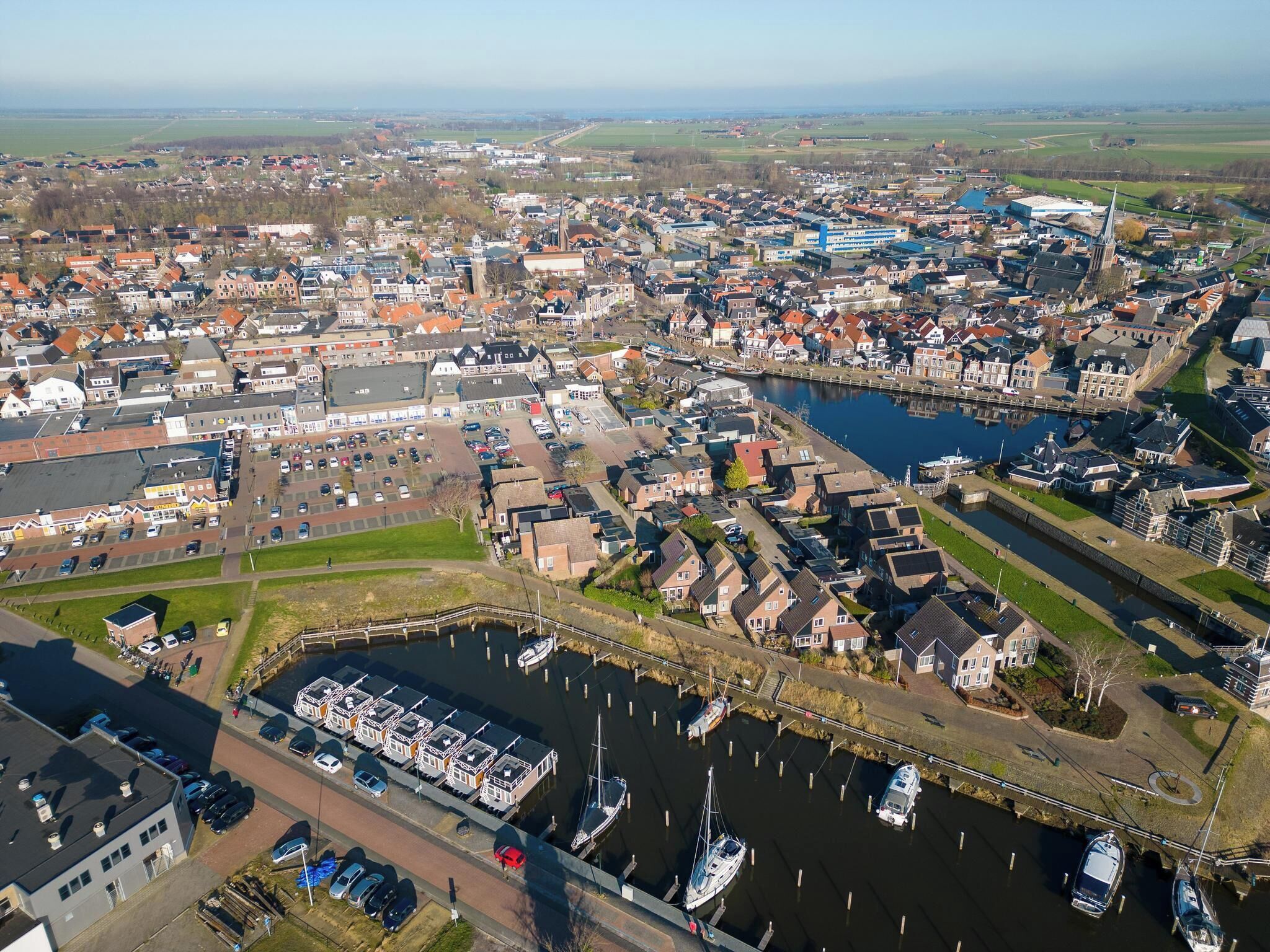 An aerial view of a town with a canal, boats, and residential buildings.