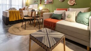 Ein modernes Wohnzimmer mit Sofa, Sesseln, Esstisch und Wanddeko.