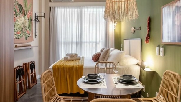 Ein Zimmer mit Esstisch für zwei Personen, Deckenventilator und großer Lampenschirm aus Bändern.