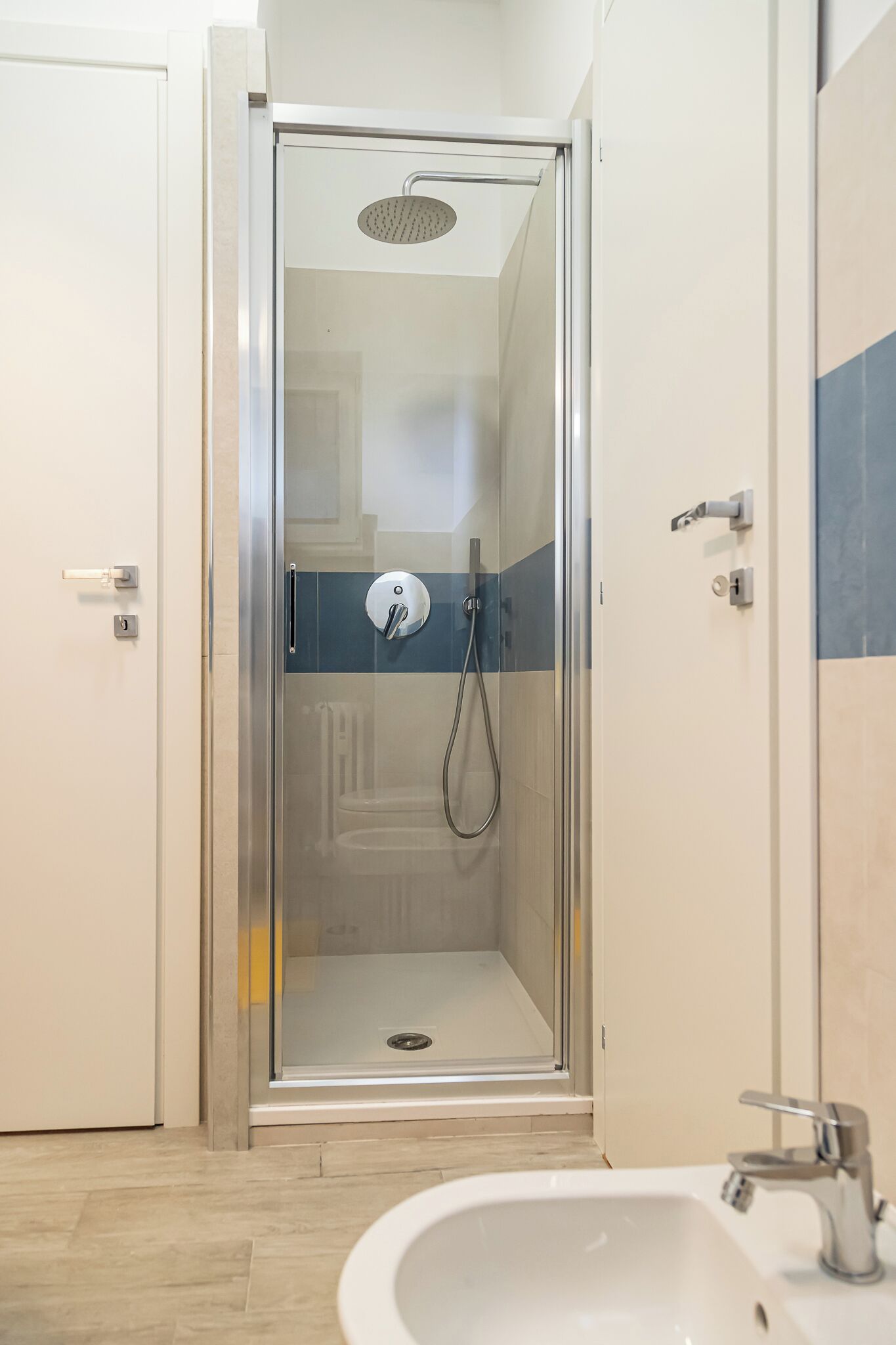 A modern bathroom with a glass-enclosed shower, a sink, and a toilet.