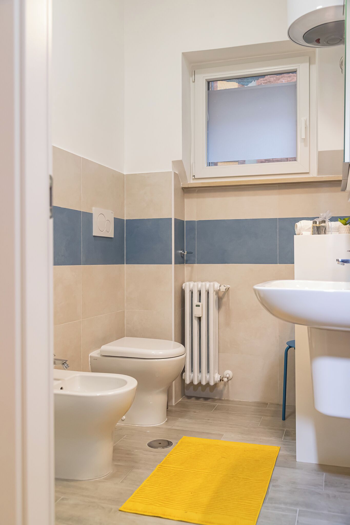 A bathroom with a toilet, bidet, and a sink.