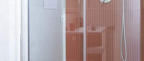 Un baño moderno con ducha acristalada, inodoro a la vista y zona de lavamanos.