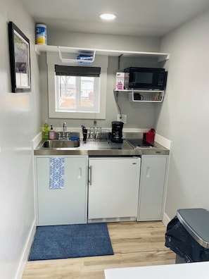 A compact kitchen with white cabinets, a stainless steel sink, a microwave, and a coffee maker.