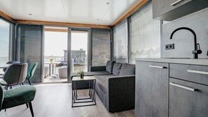 Une cuisine moderne avec des meubles gris, un robinet noir et un coin repas comprenant une table et des chaises.