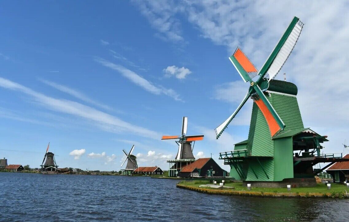 A row of traditional windmills by a body of water.