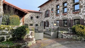 Un edificio de piedra con varias ventanas y una entrada protegida por una reja.