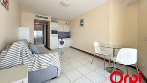 Un espacio habitable compacto con kitchenette, comedor y cama.