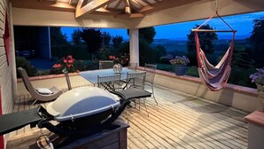Eine Terrasse im Freien mit Grill, Esstisch und Stühlen.