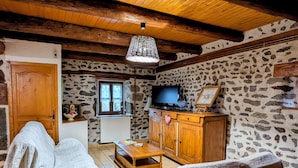 Ein gemütliches Zimmer mit Steinwand, Holzmöbeln, einem Fernseher und einem Fenster.