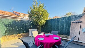 An outdoor patio with a round table covered in a bright pink tablecloth, surrounded by metal chairs. - Cozy house with AC and parking - 6 guests (Argelès-sur-Mer)
