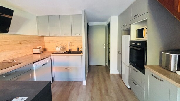 A compact kitchen with light grey cabinets, a wooden countertop, a stainless steel sink, and a microwave. - Cozy house with AC and parking - 6 guests (Argelès-sur-Mer)