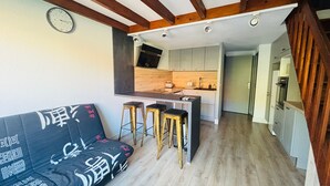 A modern kitchen with wooden beams, a sofa with Asian script, and a clock on the wall. - Cozy house with AC and parking - 6 guests (Argelès-sur-Mer)