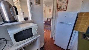 Eine kleine Küche mit Mikrowelle, Wasserkocher und Kühlschrank.